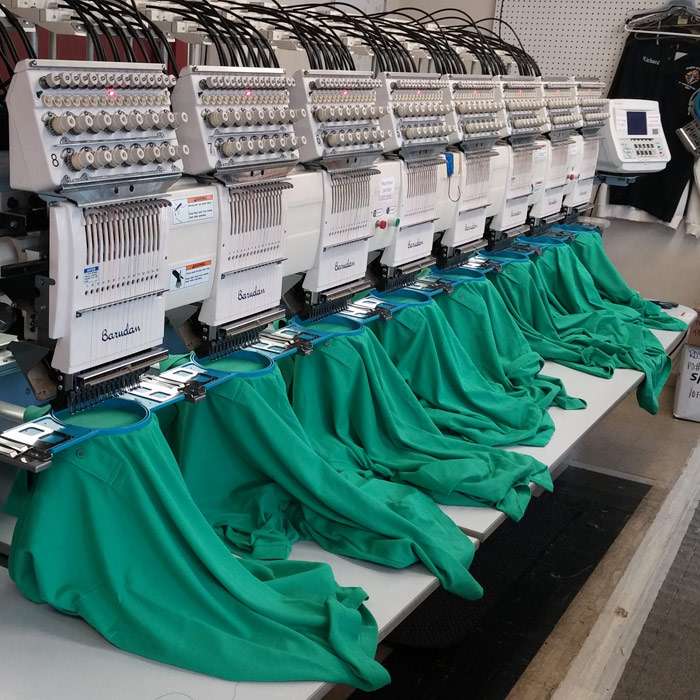 Custom embroidery printed on green shirts using machine